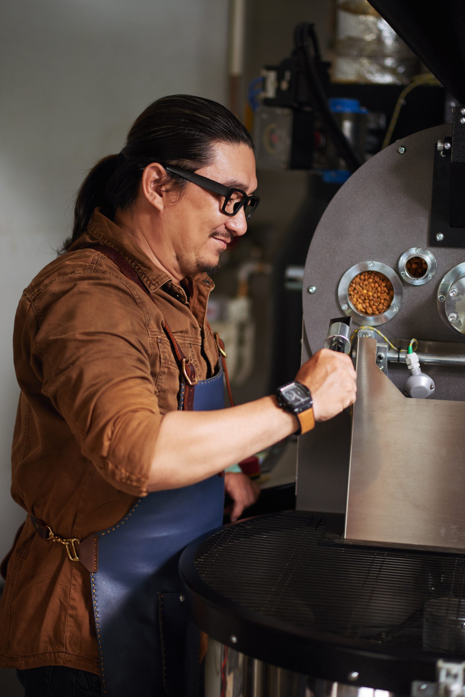 Smiling owner in glasses checking roasting coffee beans