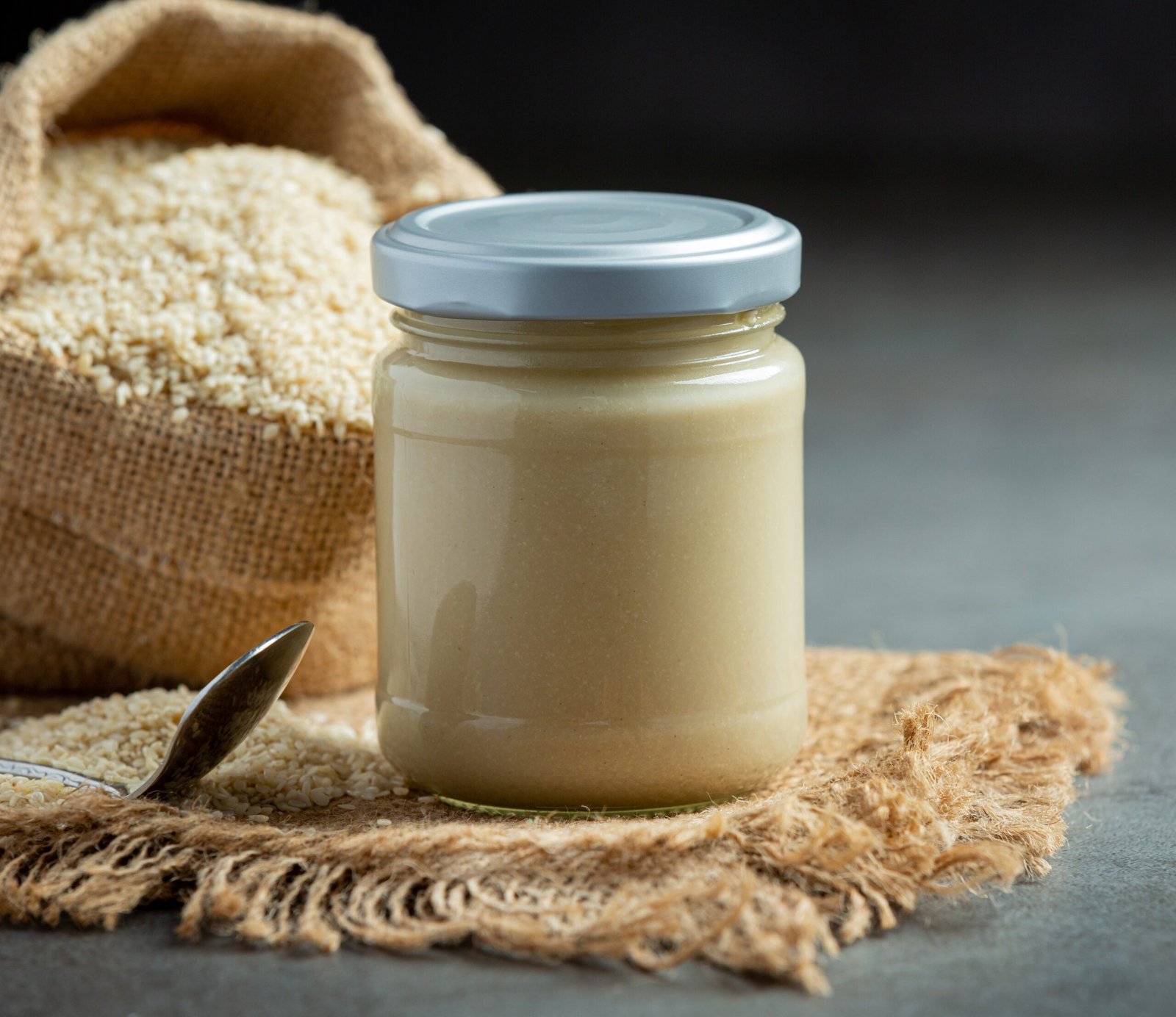 tahini and sesame seeds on dark background